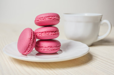 pink cookies makaroon and Cup on white wooden background