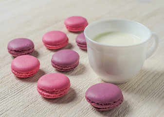 Obraz na płótnie Canvas pink cookies makaroon and Cup on white wooden background