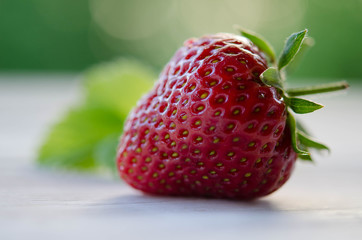 one strawberry on a wooden table