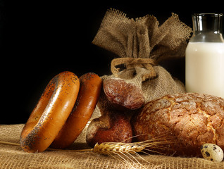 Bread, spikelets and eggs in still life on a dark background