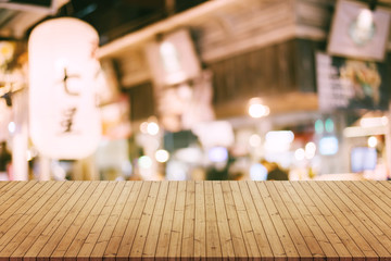 image of wooden table in front of abstract blurred background of resturant lights