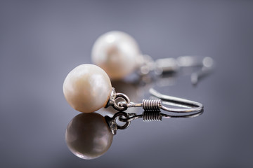 natural pearl earrings on a dark reflective surface