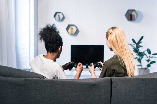 back view of multiethnic couple playing video game together at home
