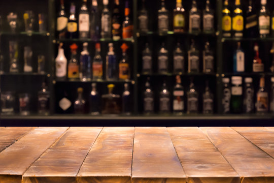 Empty wooden bar counter with defocused background and bottles of restaurant, bar or cafeteria background.