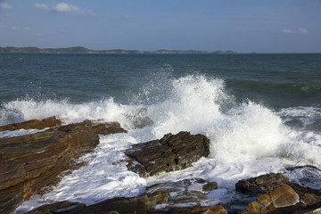 The waves breaking on a stony beach, forming a spray in Thailand