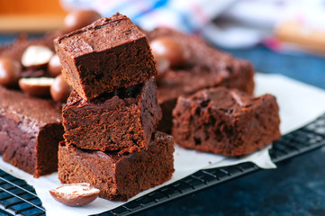 Dark chocolate brownie squares on a wire rack decorated with creamy chocolate eggs. Blue stone...