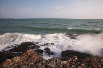 The waves breaking on a stony beach, forming a spray in Thailand