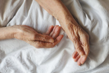 Old hands on a white background. Grandmother in bed.