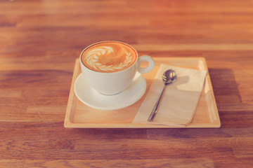 A Cup of hot latte art coffee on wooden table