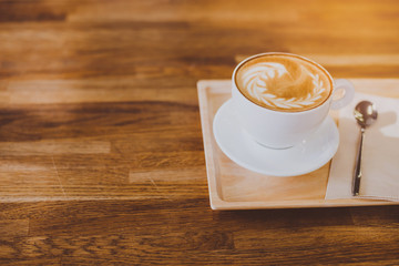 A Cup of hot latte art coffee on wooden table