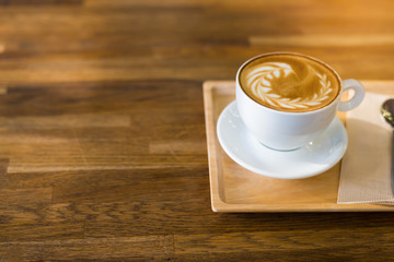 A Cup of hot latte art coffee on wooden table