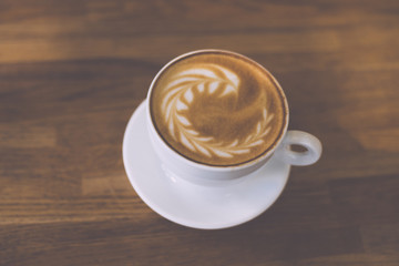 A Cup of hot latte art coffee on wooden table