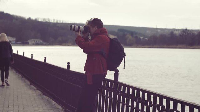 Traveler photographer shoots beautiful sunset on the lake shore