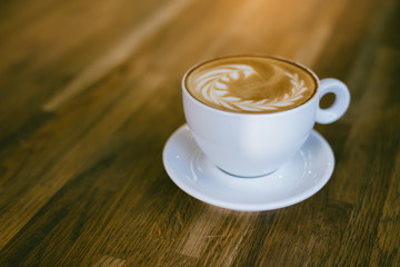 A Cup of hot latte art coffee on wooden table