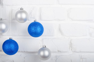 Christmas blue and silver balls on white brick wall holiday background with place for text