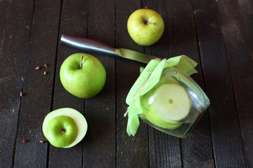 water with green Apple in jar on wooden background