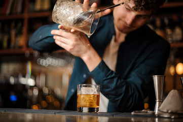 barman finishes preparing an alcoholic cocktail Old Fashioned
