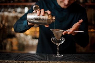 Fototapeta na wymiar barman poured an alcoholic cocktail from a shaker into a glass
