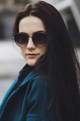Beautiful brunette girl. Fashionable, stylish with black hair, in a coat and jeans