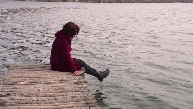 Beautiful woman sitting on a old bridge and looking at her