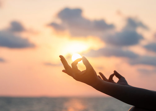 Mantra yoga meditation practice with silhouette of woman in lotus pose having peaceful mind relaxation on the beach outdoor training with sunset golden hour heavenly sky 