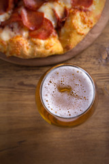 Beer and pepperoni pizza on wooden table. Glass of beer. Ale and food concept. overhead, vertical