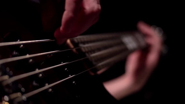 Musician playing five string electric bass guitar macro