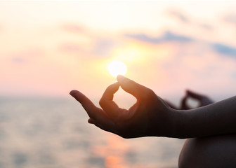 Naklejka na ściany i meble Mantra yoga meditation practice with silhouette of woman in lotus pose having peaceful mind relaxation on the beach outdoor training with sunset golden hour heavenly sky