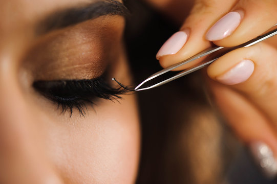 Close up of professional stylist lengthening lashes for female client in a beauty salon.