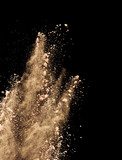 Abstract colored brown powder explosion isolated on black background.