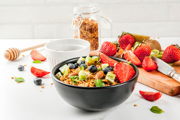 Healthy breakfast with muesli or granola with nuts and fresh berries and fruits - strawberry, blueberry, kiwi, on white table, copy space