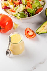 Classic honey mustard salad dressing, with fresh vegetables on white marble table, copy space
