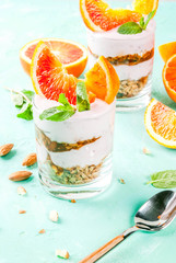 Healthy breakfast, Blood Orange Parfait with granola. yogurt, almond and mint, light blue background, copy space