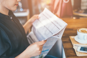 A young attractive woman reading newspapers at a cafeteria