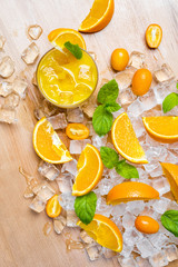 Mixture of sliced fresh citrus fruits, orange, lime, lemon and kumquat for squeezing juice on ice and wooden table