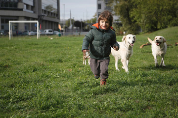 Little boy playing and running with his two dogs