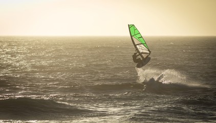 Male surfer surfing with surfboard and kite