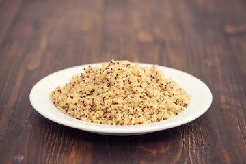 boiled quinoa on white plate on wooden background