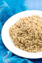 boiled quinoa on white plate on wooden background