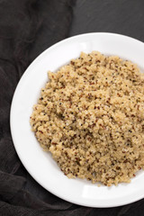 boiled quinoa on white plate on black ceramic background