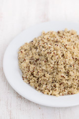 boiled quinoa on white plate on wooden background
