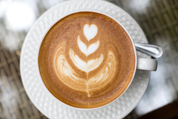 Top view image of a cup of hot latte coffee with latte art on table