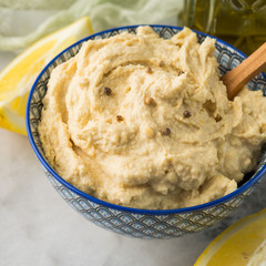 Mashed chickpeas Hummus dip with tahini and lemon juice and oil in bowl on marble board