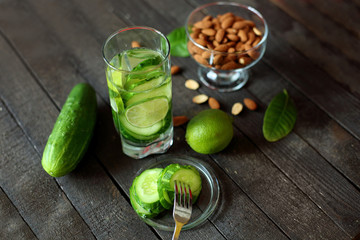 water with cucumber and lime on wooden background