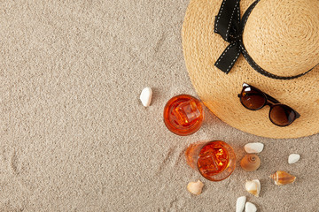 Fototapeta na wymiar top view of straw hat, cocktails, seashells and sunglasses on sand