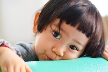 Cute asian baby girl with gray sweater is looking at camera, selective focus