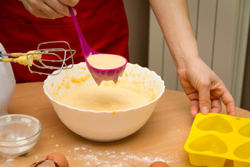 The woman's hand pours the ingredient for cakes into the mold. Ready for cakes