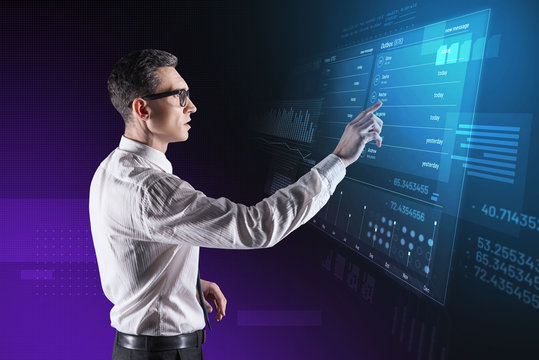 Important information. Clever attentive data scientist standing in front of a futuristic transparent device and touching the screen of it