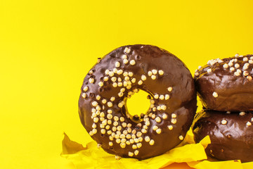 chocolate donut lies one on the other, on a yellow background