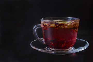 one aromatic glass mug of fruit tea on a black background